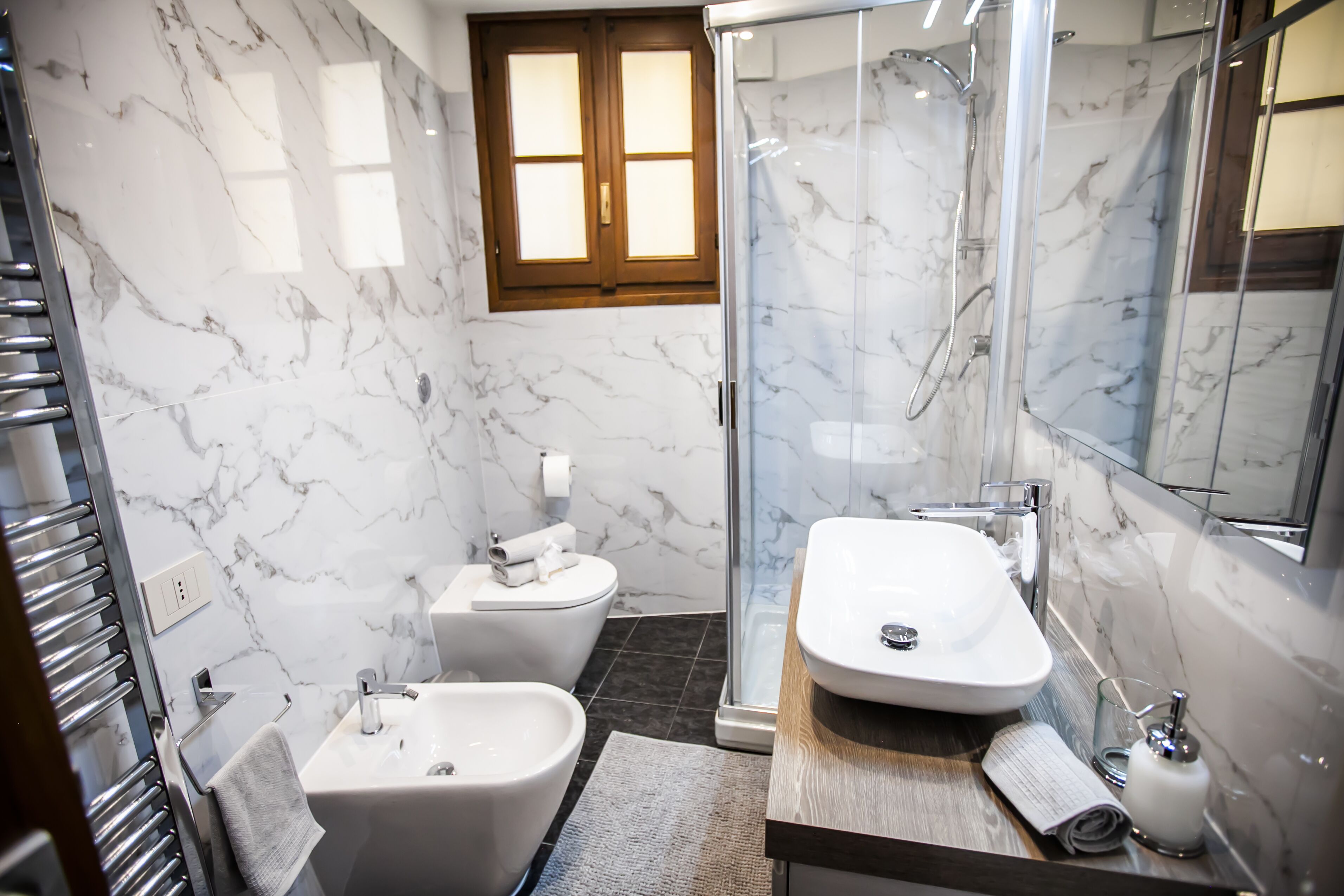 A modern bathroom with a glass-enclosed shower, a freestanding bathtub, and a vanity with a mirror.