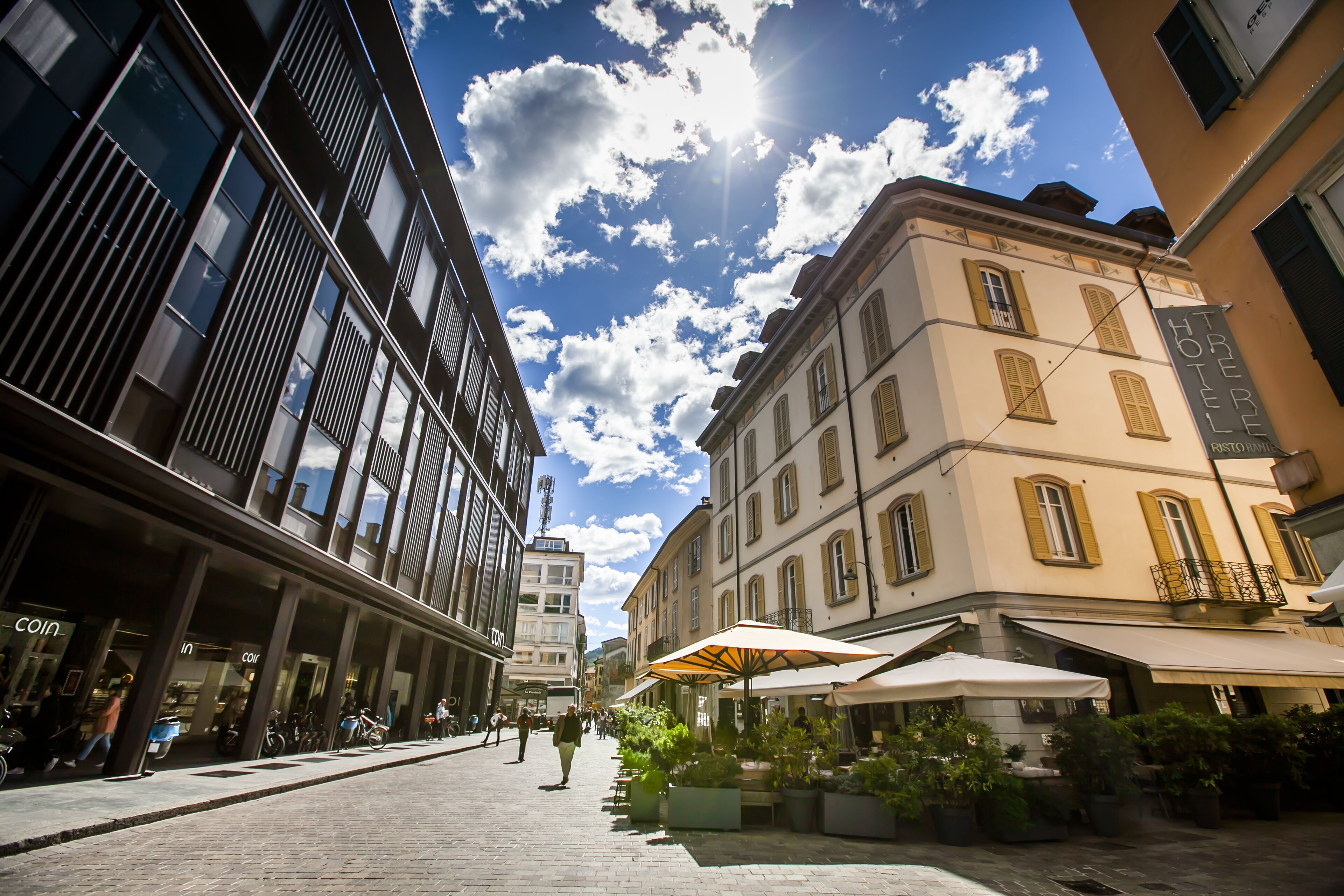 A street with a hotel named "TRIPE HOTEL" and outdoor seating with umbrellas.