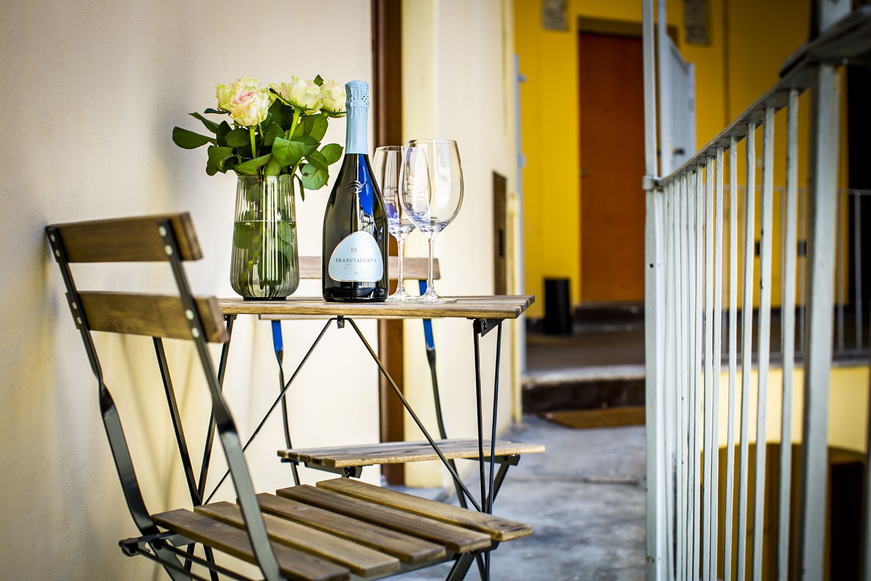 A table with a bottle of wine, a glass, and a vase with flowers.