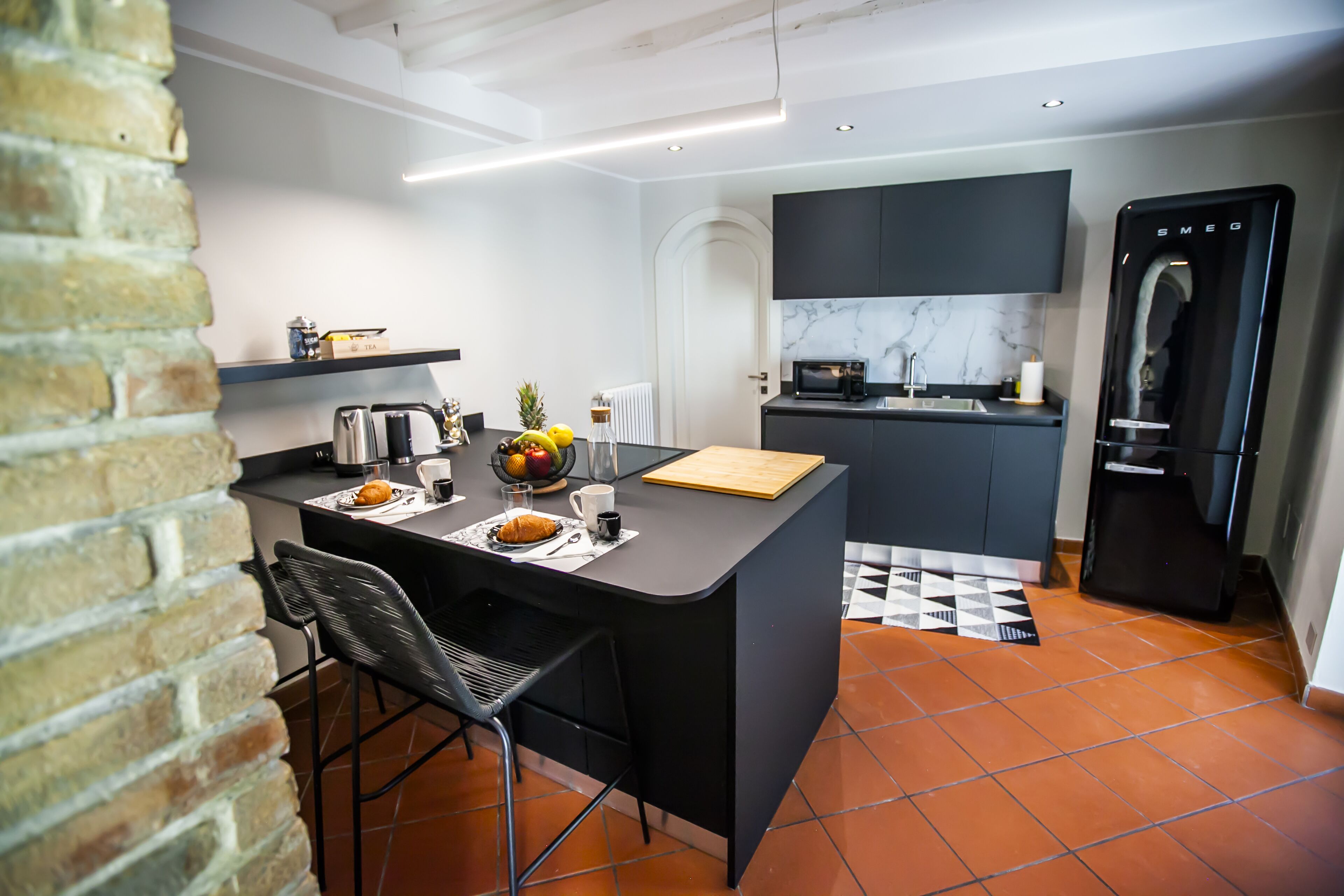 A modern kitchen with a black countertop, a built-in microwave, and a black refrigerator.