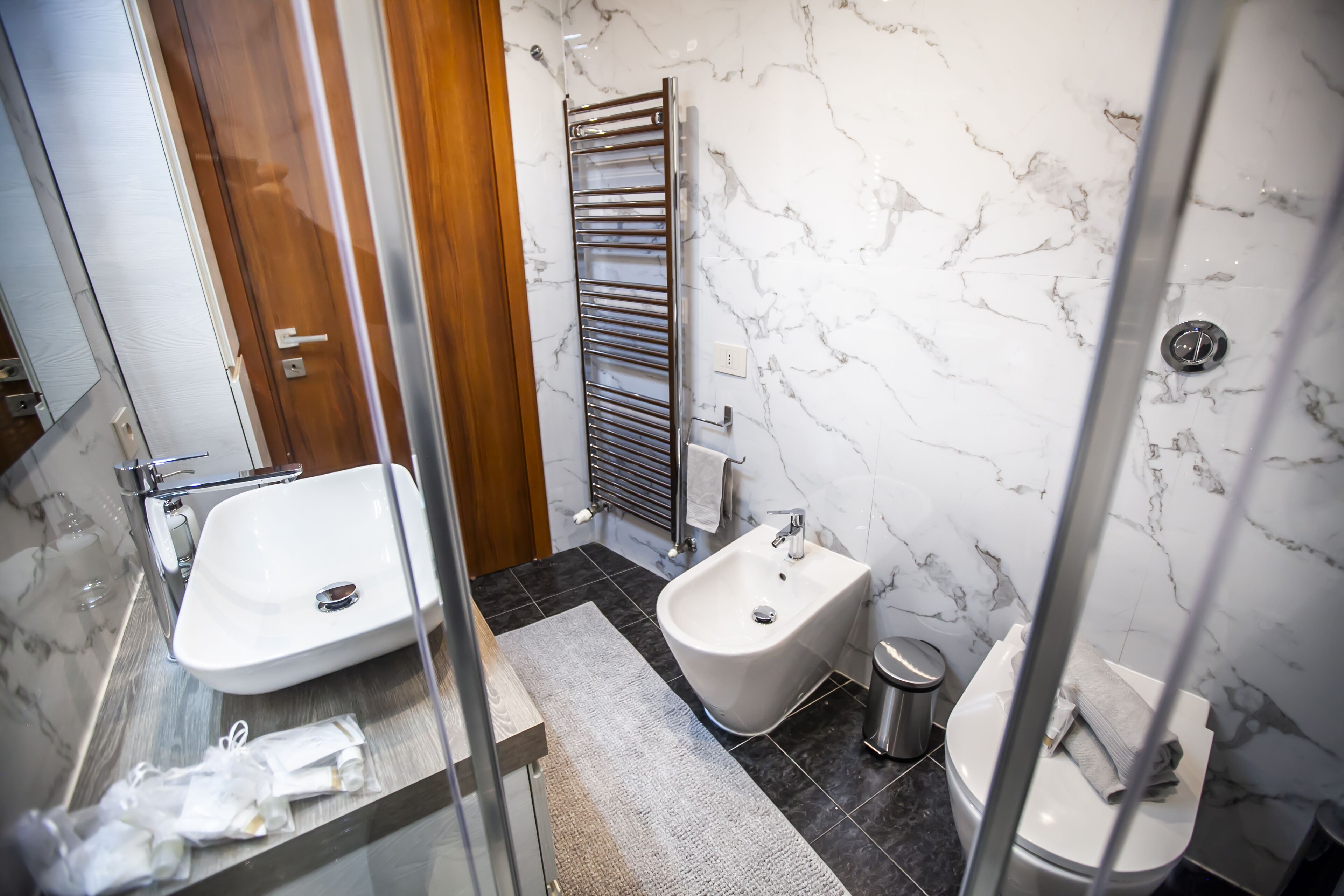 Ein modernes Badezimmer mit Duschkabine aus Glas, einem Bidet, einer Toilette und einem Waschbecken.
