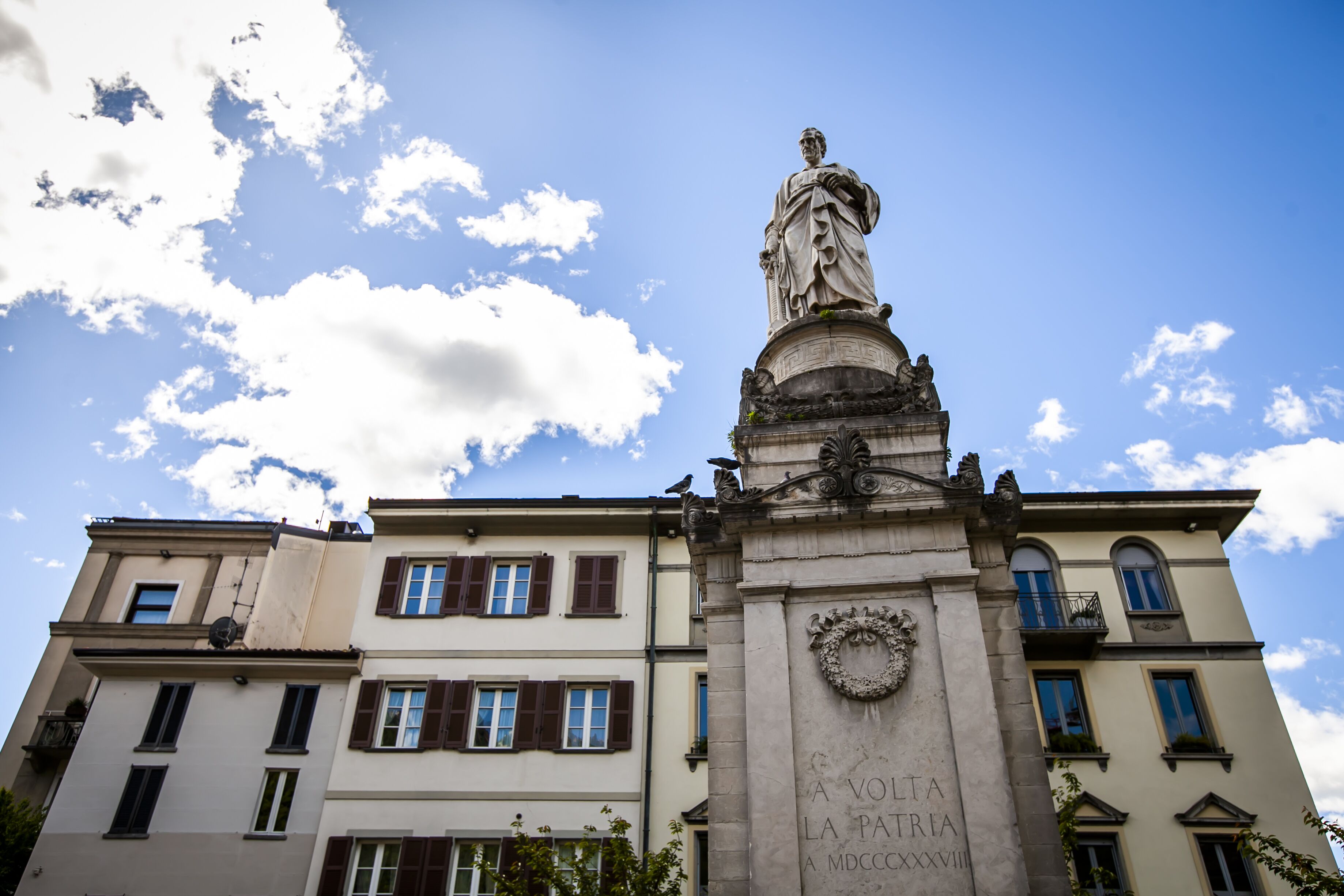 Un edificio con una statua sulla sommità, caratterizzato da una targa con iscrizioni.