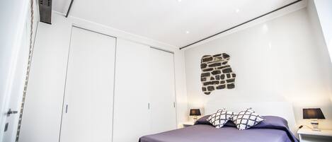 A bedroom with a bed, nightstands, a wardrobe, and a stone wall decoration.