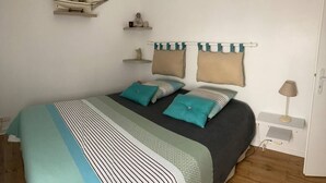 Une chambre à coucher bien rangée, avec un lit, des oreillers, une table de chevet, une lampe et des décorations murales.