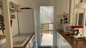 Une cuisine compacte avec des meubles blancs, un four encastré, un évier et une machine à café.