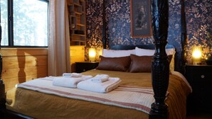 A bedroom with a large bed, wooden headboard, floral wallpaper, and bedside lamps.