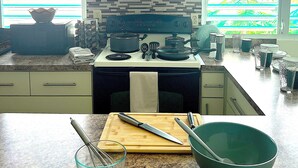 A modern kitchen with white cabinets, a granite countertop, and a view through the windows.