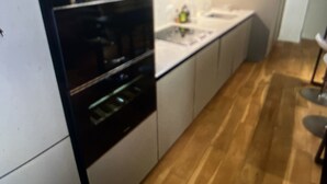 A modern kitchen with white cabinets, a black oven, and a wooden countertop. - LOFT Saint Germain des Prés. (Paris)