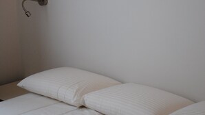 A neatly made bed with white bedding and a wall-mounted light fixture above it. - LOFT Saint Germain des Prés. (Paris)