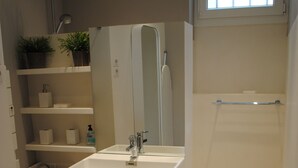 A bathroom with a white sink, mirror, and shelves with toiletries. - LOFT Saint Germain des Prés. (Paris)