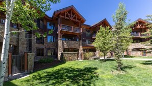 A multi-story lodge with stone and wood architecture, featuring balconies and a well-maintained lawn. - Multiple Hot Tubs | Walk to Slopes | Free Winter Shuttle (Steamboat Springs)