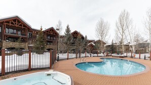 A pool area with a hot tub, surrounded by wooden buildings and a brick walkway. - Multiple Hot Tubs | Walk to Slopes | Free Winter Shuttle (Steamboat Springs)