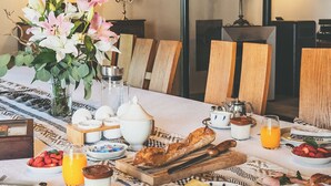 Una mesa de desayuno lista para dos personas, con platos de comida, un jarrón de flores y diferentes opciones para el desayuno.