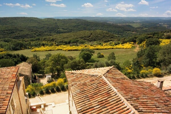 A view of terracotta-roofed buildings with a rural landscape in the background.