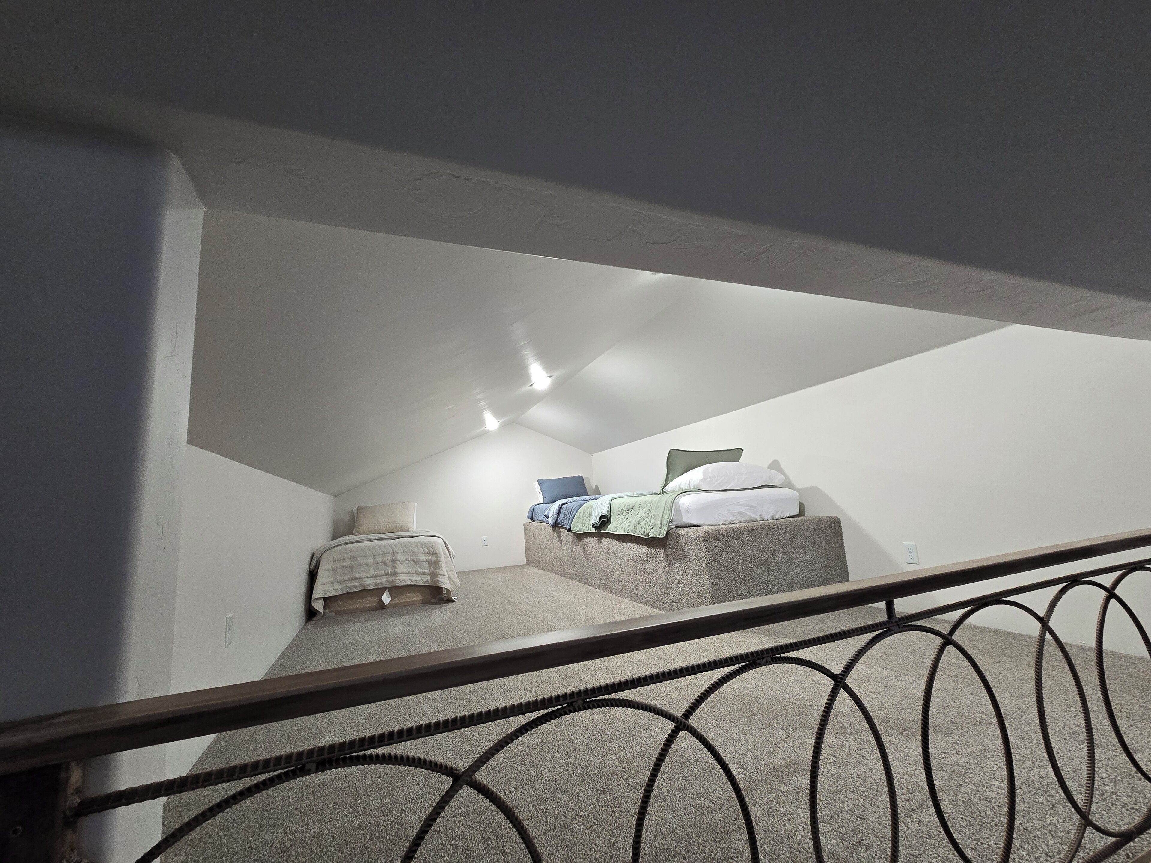 A small, narrow stairwell leading to a loft bedroom with a bed and a nightstand.