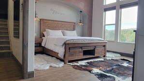 Une chambre à coucher avec un lit en bois, un ventilateur de plafond et de grandes fenêtres.