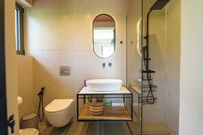 Une salle de bain moderne avec un lavabo, des toilettes et une douche, le tout de couleur blanche.