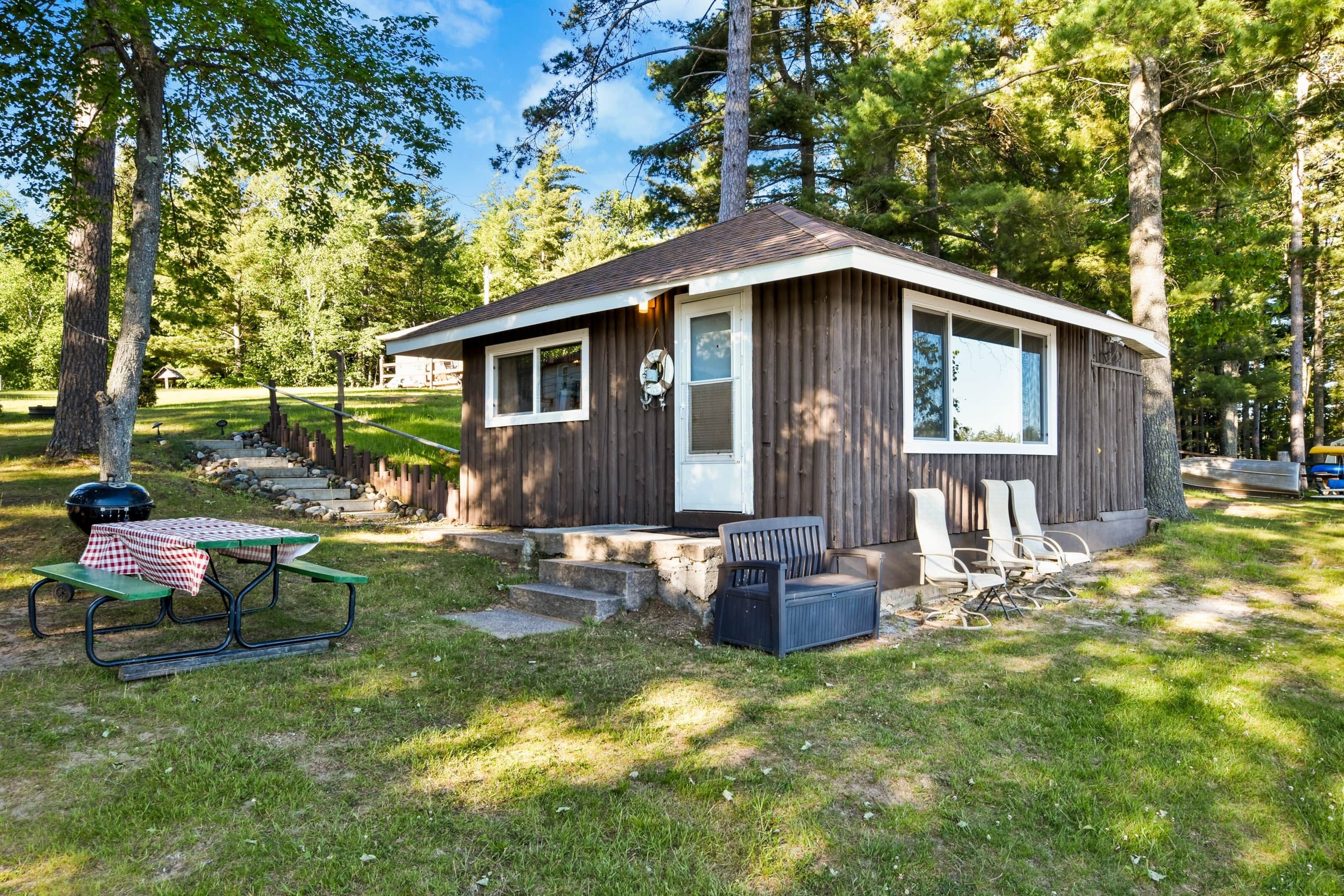 A small cabin with a porch, a picnic table, and outdoor seating.