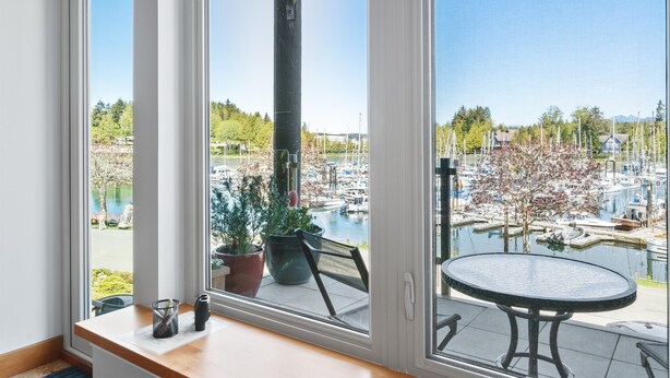 A room with a large window overlooking a marina with boats and trees.