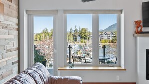 A modern living room with a large window overlooking a marina and buildings.