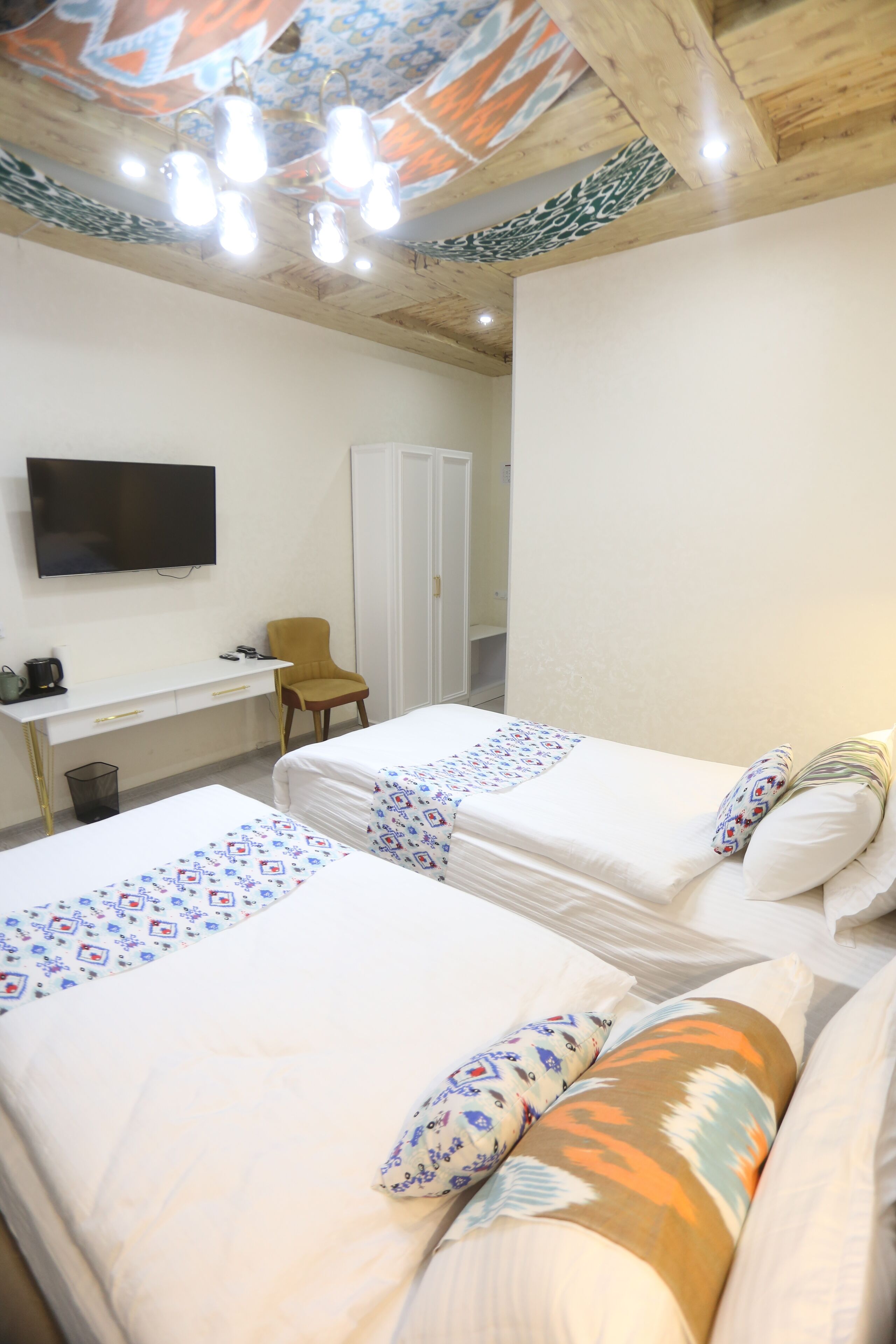 A hotel room with two beds, a desk, a chair, a television, and a wardrobe.