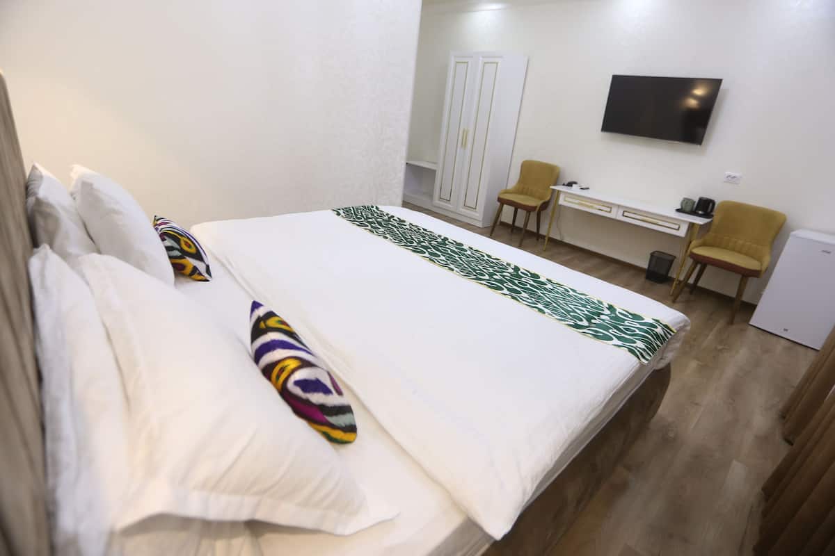 A hotel room with a bed, a desk, a chair, a TV, and a wardrobe.