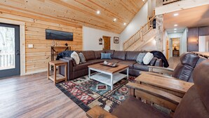 Ein großzügiges Wohnzimmer mit einer großen Eckcouch, einem Holztisch und einem gemusterten Teppich.