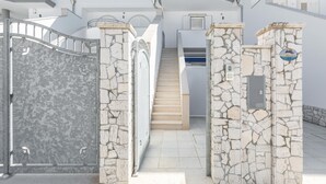 A white building with a stone staircase leading to a door with a metal gate. - 3852 Dolly House - Primo Piano by Barbarhouse (Porto Cesareo)