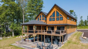 Eine zweigeschossige Blockhütte mit überdachter Veranda, Sitzbereich im Freien und Whirlpool.