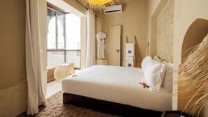 Une chambre dotée d’un grand lit, d’un luminaire suspendu, d’un balcon et offrant une vue sur l’extérieur.