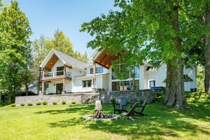 A two-story house with a stone retaining wall, a fire pit, and outdoor seating.