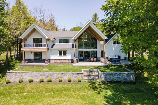 A two-story house with a balcony, a large window, and a stone retaining wall.