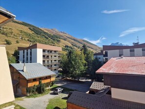 Zona residencial con edificios de varios pisos, un estacionamiento y montañas al fondo.
