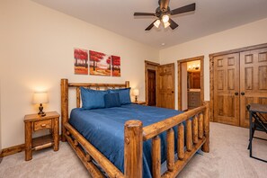 A bedroom with a wooden bed frame, a ceiling fan, and a nightstand with a lamp.