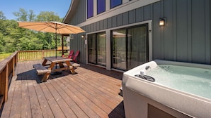 En træterrasse med jacuzzi, picnicbord og parasol.