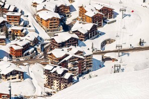 A snow-covered ski resort with multiple wooden buildings, ski lifts, and a chairlift.