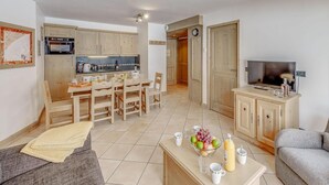 En kompakt bolig med tekøkken, spiseplads og opholdsområde med sofa og fjernsyn.