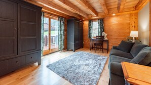 A log cabin interior with a wooden ceiling, a dark wooden wardrobe, a grey sofa, and a dining area with a table and chairs. - Dog Friendly Lodge w/ Hot Tub & Views (McHenry)
