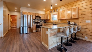 A modern kitchen with wooden cabinetry, stainless steel appliances, and a central island with bar stools.