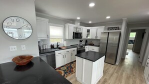 A modern kitchen with white cabinetry, a black countertop, and a stainless steel refrigerator. - AMAZING WATERFRONT HOME WITH HOT TUB. BOTH HAVE EXTENSIVE VIEWS OF THE LAKE (Cookson)