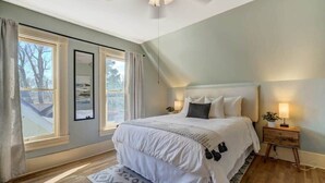 Ein Schlafzimmer mit einem großen Bett, einem Nachttisch und einem Fenster mit Vorhängen.