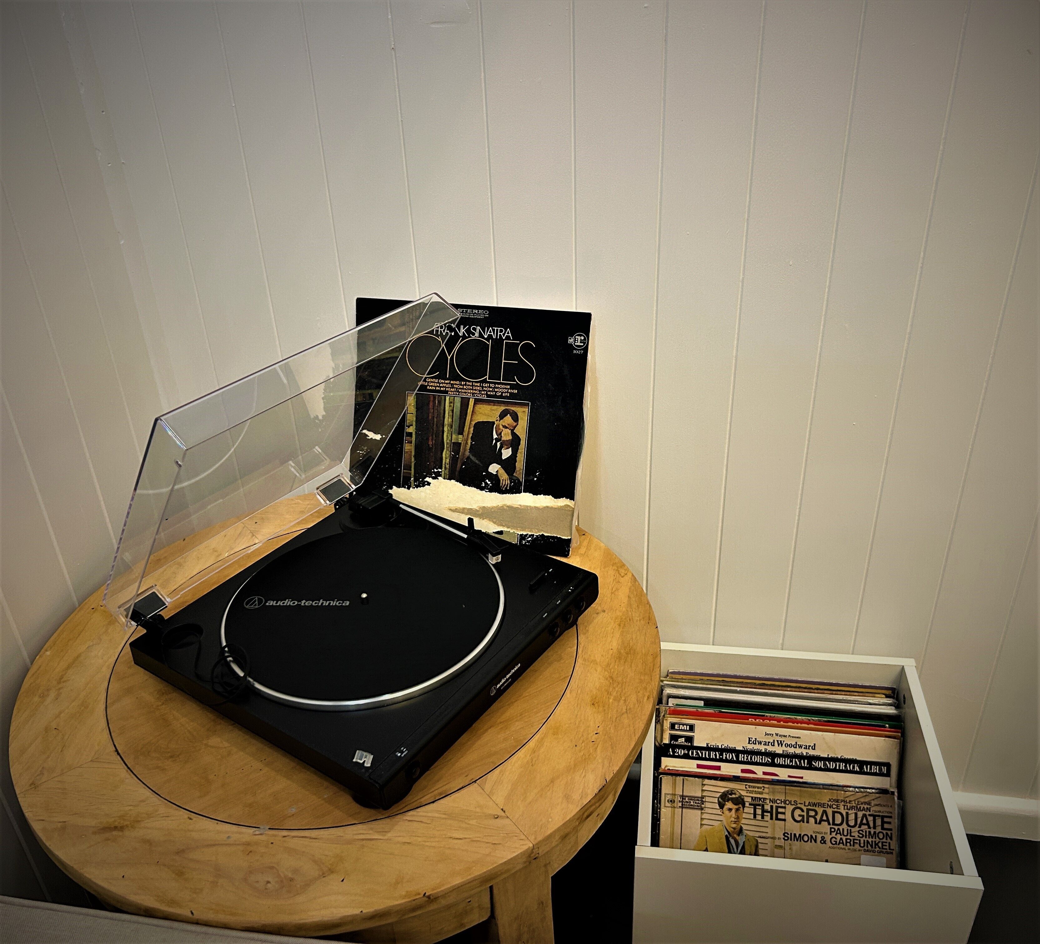 A turntable with a record, a record sleeve, and a CD player on a wooden table.