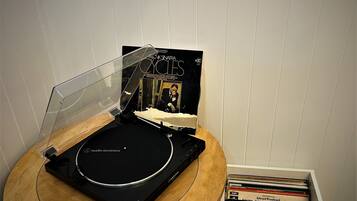 A turntable with a record, a record sleeve, and a CD player on a wooden table.