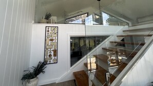 Een modern interieur met een glazen trap, witte muren en een geometrisch kunstwerk.
