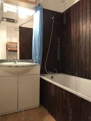 Ein Badezimmer mit Holzwand, Waschbecken und Badewanne.