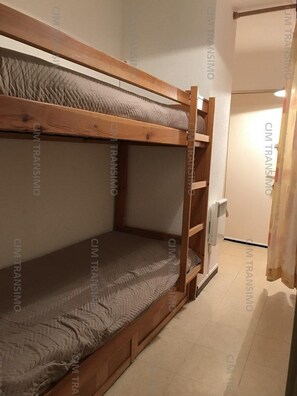 Ein Stockbett in einem Zimmer mit Fliesenboden und einer Tür im Hintergrund.