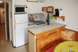 A compact kitchen with a refrigerator, microwave, sink, and wooden cabinets. - 10m from ski slopes, 3rd floor, view mountain, balcony, tv, ski locker, 28m², Les Orres (Les Orres)