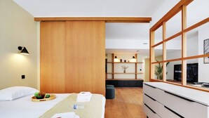 A modern hotel room with a bed, a wooden partition, a desk with drawers, and a shelf with decorative items. - Superb Appartement: 3br/8p - Père Lachaise (Paris)