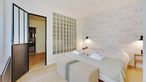 A bedroom with a bed, bedside tables, a mirror, and a wall with a mosaic pattern. - Charming Appart 4p/1br G Le Marais (Paris)