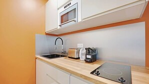 A modern kitchen with a built-in microwave, a toaster, and a coffee maker on the countertop. - Charming Appart 4p/1br G Le Marais (Paris)